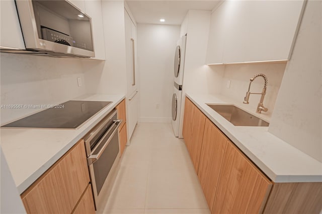 kitchen with light stone countertops, appliances with stainless steel finishes, white cabinetry, and sink