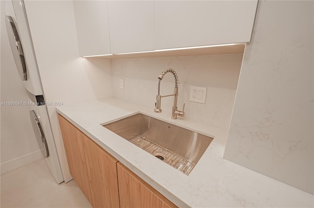 kitchen featuring tasteful backsplash, white cabinetry, sink, and light stone countertops