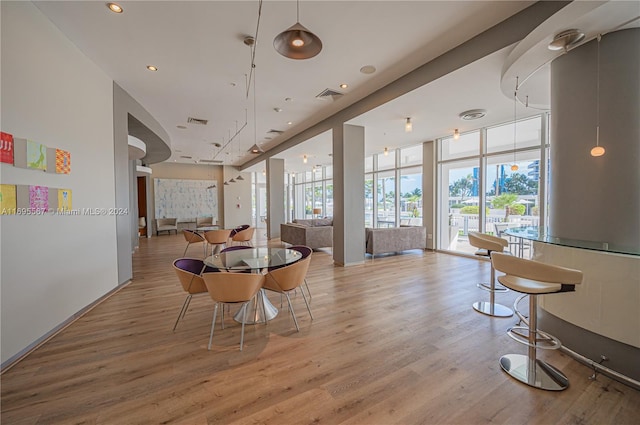 dining room with expansive windows, a healthy amount of sunlight, and light hardwood / wood-style flooring