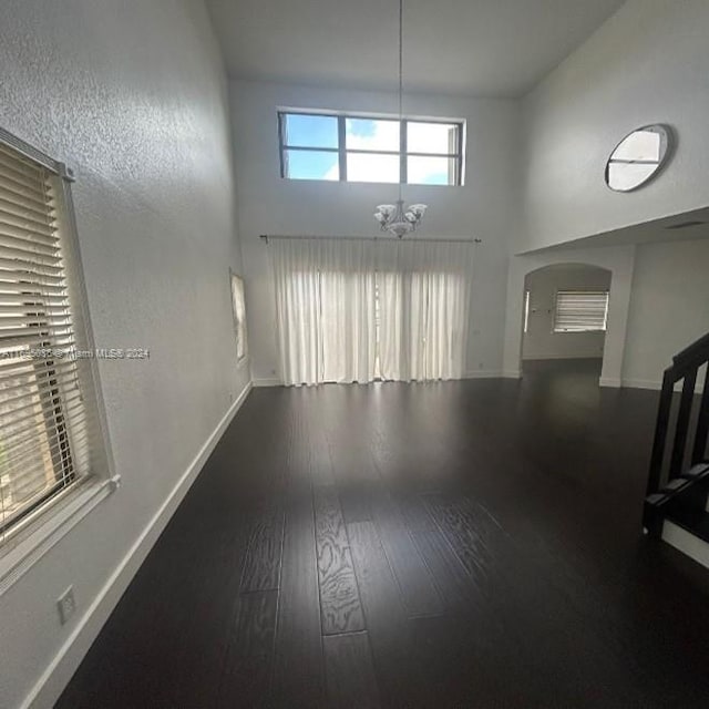 unfurnished room featuring hardwood / wood-style flooring, a high ceiling, and a chandelier