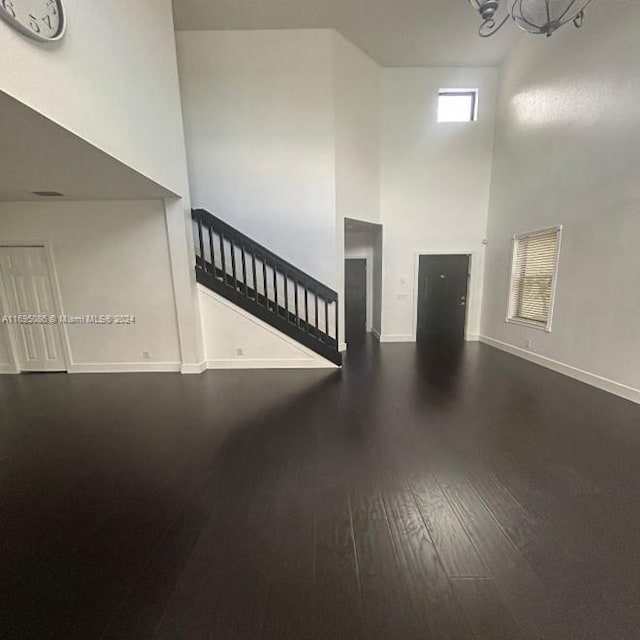 interior space featuring a high ceiling, dark hardwood / wood-style floors, and an inviting chandelier