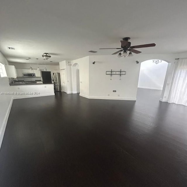 unfurnished living room featuring ceiling fan, dark hardwood / wood-style flooring, and a healthy amount of sunlight