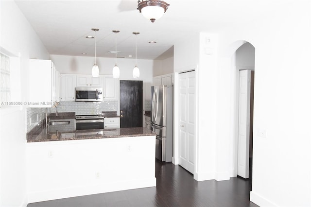 kitchen featuring dark wood-type flooring, kitchen peninsula, pendant lighting, white cabinets, and appliances with stainless steel finishes