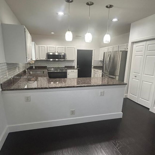 kitchen with pendant lighting, white cabinets, appliances with stainless steel finishes, tasteful backsplash, and kitchen peninsula