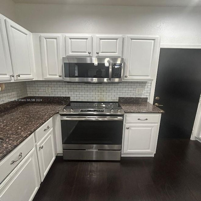 kitchen featuring white cabinets, decorative backsplash, dark stone countertops, appliances with stainless steel finishes, and dark hardwood / wood-style flooring