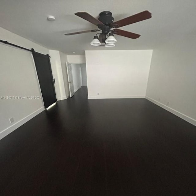 spare room with a barn door and ceiling fan