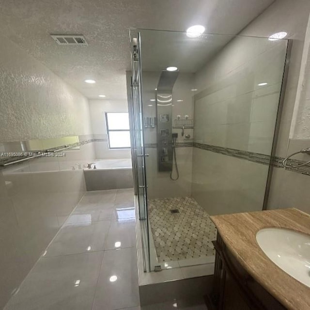 bathroom with vanity, tile patterned flooring, plus walk in shower, and a textured ceiling