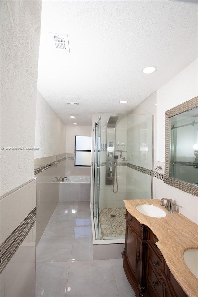 bathroom featuring plus walk in shower, a textured ceiling, vanity, and tile patterned flooring