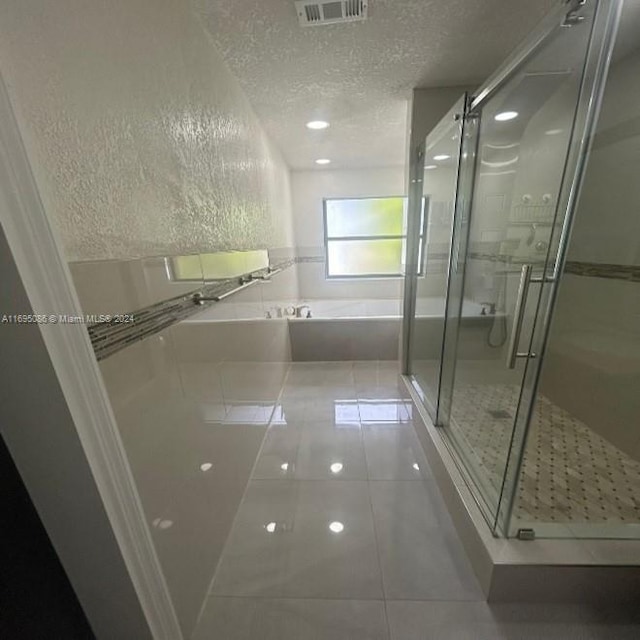 bathroom with tile patterned floors, shower with separate bathtub, and a textured ceiling