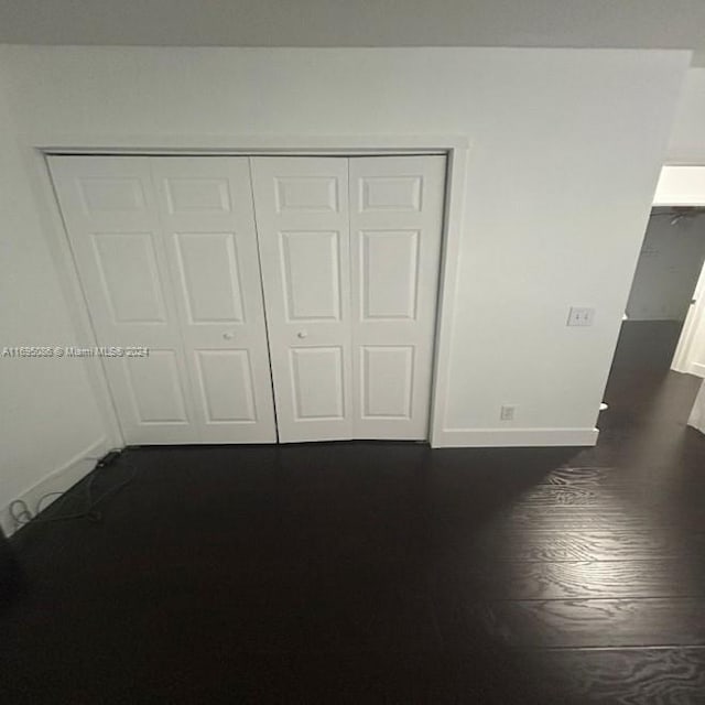 unfurnished bedroom with a closet and dark wood-type flooring