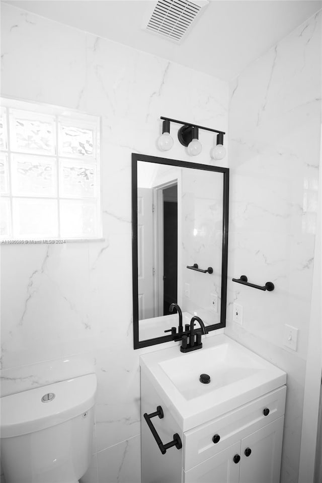 bathroom featuring vanity, toilet, and tile walls