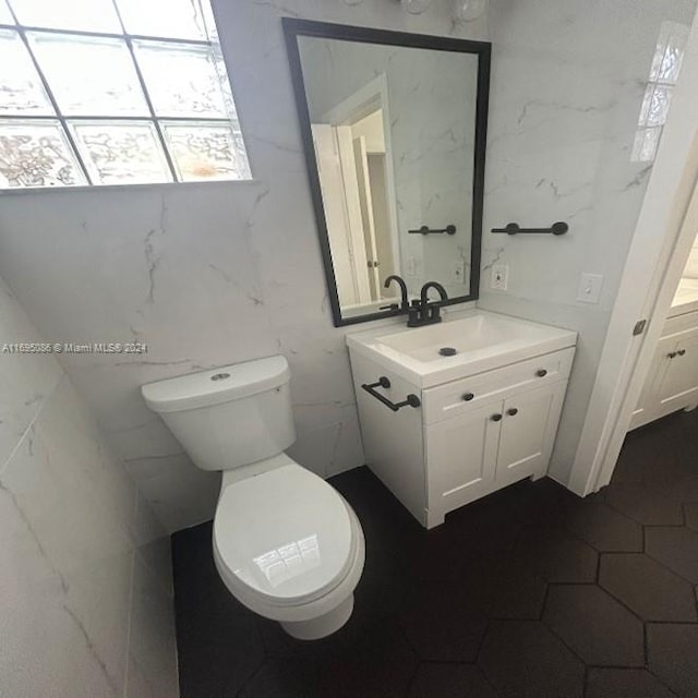 bathroom featuring vanity, toilet, and tile walls