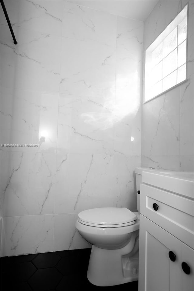 bathroom featuring vanity, toilet, and tile walls