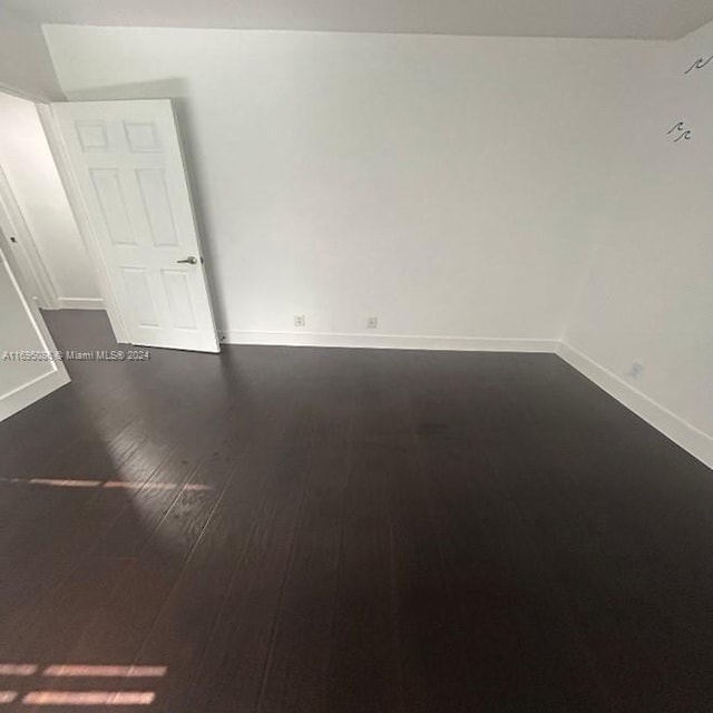 unfurnished room with dark hardwood / wood-style flooring