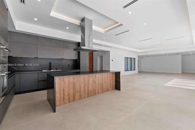 kitchen with sink, a spacious island, island exhaust hood, and a tray ceiling