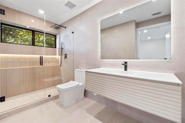 bathroom with vanity, a shower with door, toilet, and tile walls