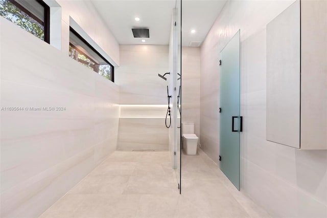 bathroom with a shower with shower door and toilet