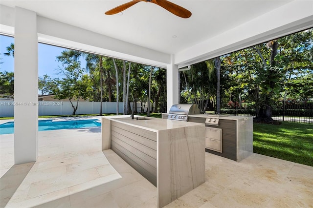 view of patio / terrace with an outdoor kitchen, ceiling fan, sink, grilling area, and a fenced in pool