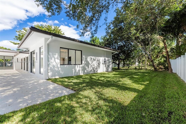 view of side of home with a lawn and a patio area