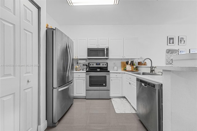 kitchen with sink, white cabinetry, stainless steel appliances, and light tile patterned floors