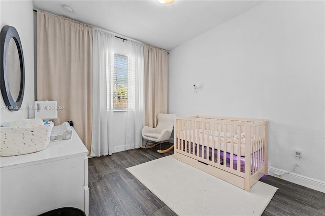 bedroom with dark wood-type flooring and a crib