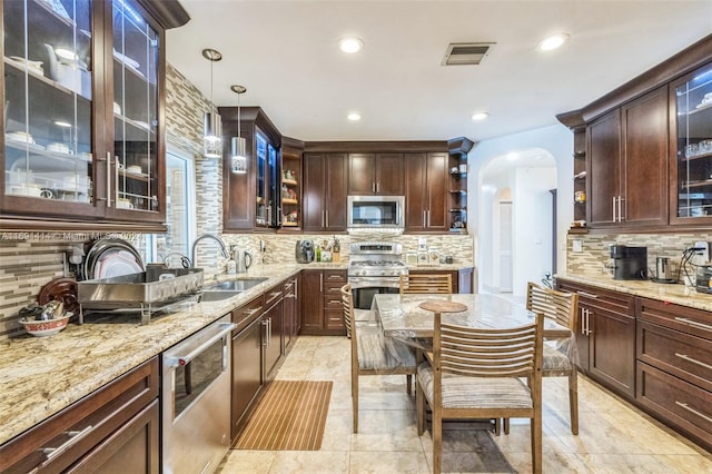 kitchen with decorative backsplash, appliances with stainless steel finishes, decorative light fixtures, light stone counters, and dark brown cabinets