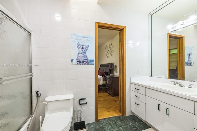 bathroom featuring tile walls, hardwood / wood-style floors, vanity, and an enclosed shower