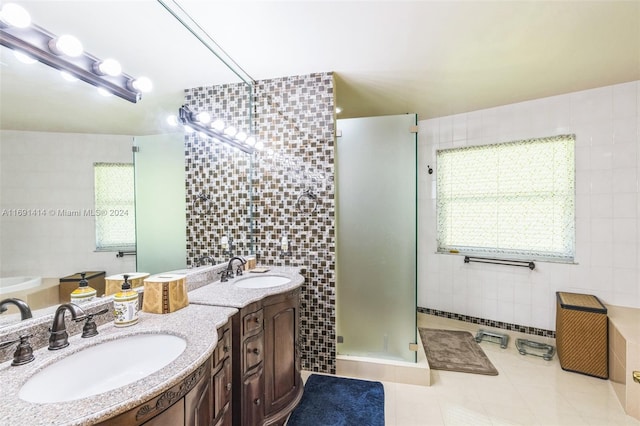 bathroom with tile patterned floors, vanity, shower with separate bathtub, and tile walls