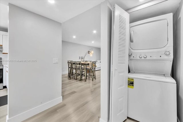 laundry area with stacked washer and dryer and light wood-type flooring