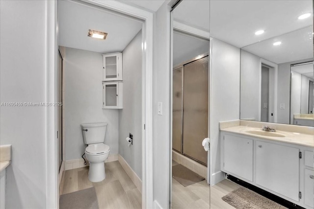 bathroom with hardwood / wood-style flooring, vanity, toilet, and an enclosed shower