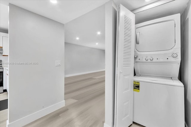 washroom with light hardwood / wood-style floors and stacked washer and clothes dryer