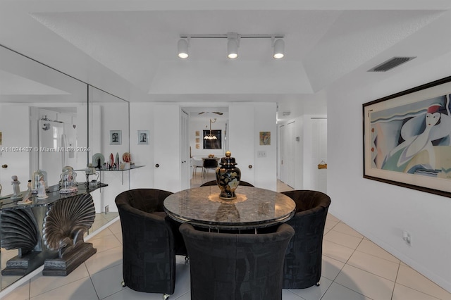 tiled dining area with a tray ceiling