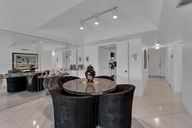 tiled dining area with a tray ceiling