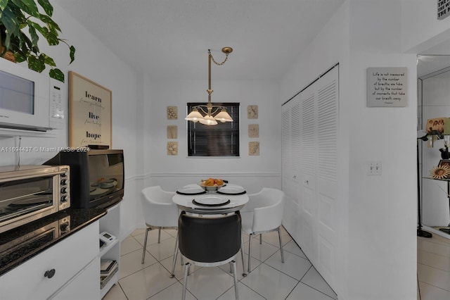 dining room with light tile patterned flooring and a notable chandelier