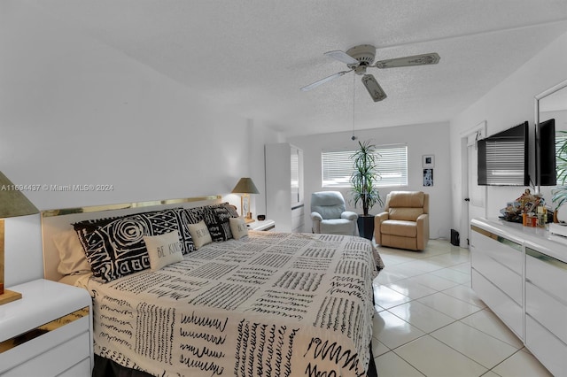 bedroom featuring ceiling fan, light tile patterned floors, and a textured ceiling