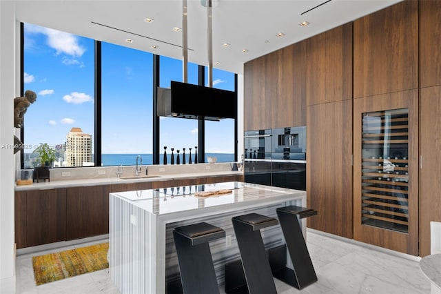 kitchen featuring a kitchen breakfast bar, a kitchen island, sink, and beverage cooler