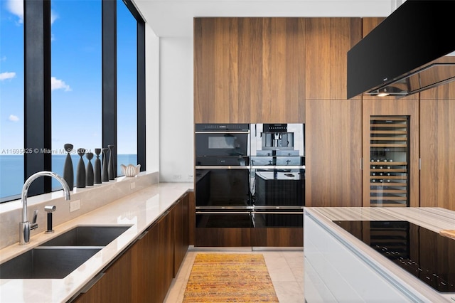 kitchen with light stone countertops, a water view, light tile patterned flooring, and sink