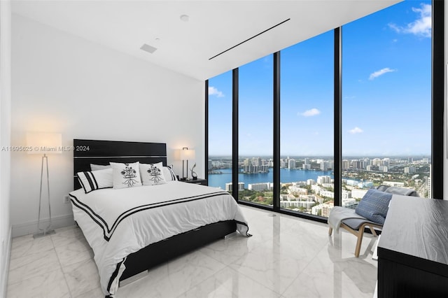 bedroom with a wall of windows, a water view, and multiple windows