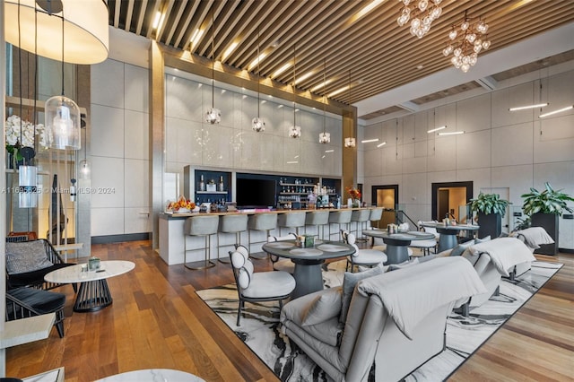 dining area with hardwood / wood-style floors, a high ceiling, and tile walls