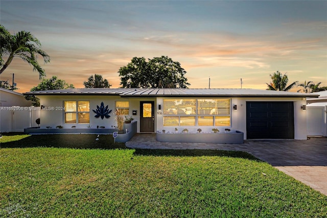 single story home featuring covered porch, a garage, and a yard