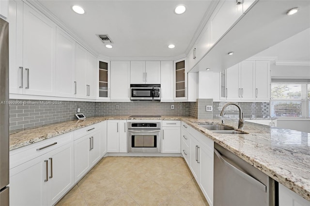 kitchen featuring light stone countertops, sink, backsplash, white cabinets, and appliances with stainless steel finishes