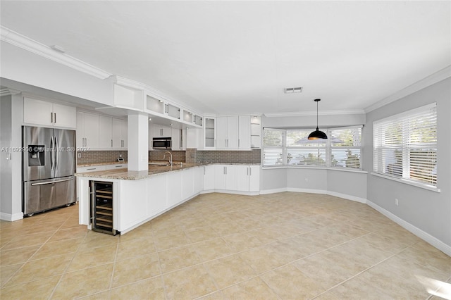 kitchen featuring light stone countertops, white cabinetry, stainless steel appliances, backsplash, and decorative light fixtures