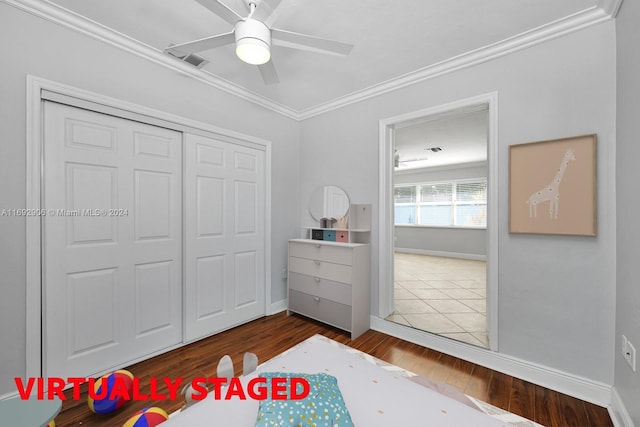 bedroom featuring a closet, dark hardwood / wood-style floors, ceiling fan, and crown molding