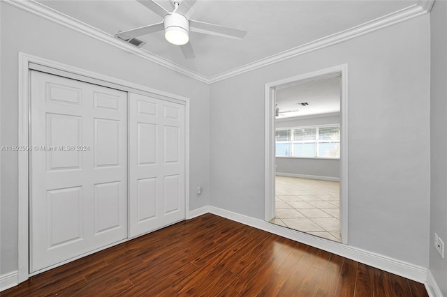 unfurnished bedroom with hardwood / wood-style floors, a closet, ceiling fan, and crown molding