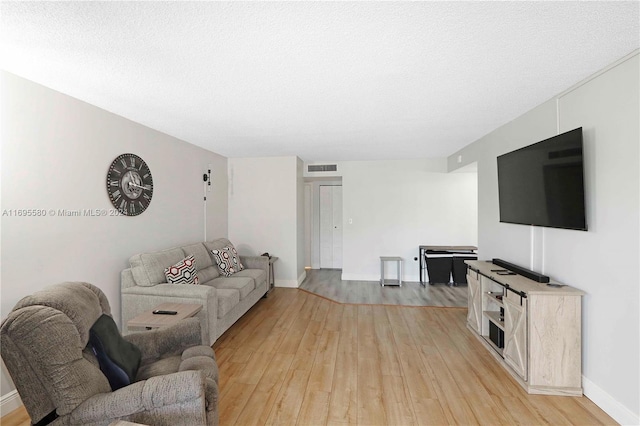 living room featuring light hardwood / wood-style flooring and a textured ceiling