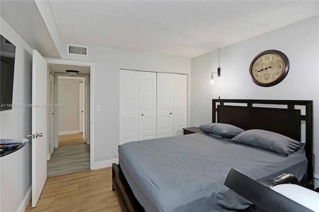 bedroom with a textured ceiling, light hardwood / wood-style floors, and a closet