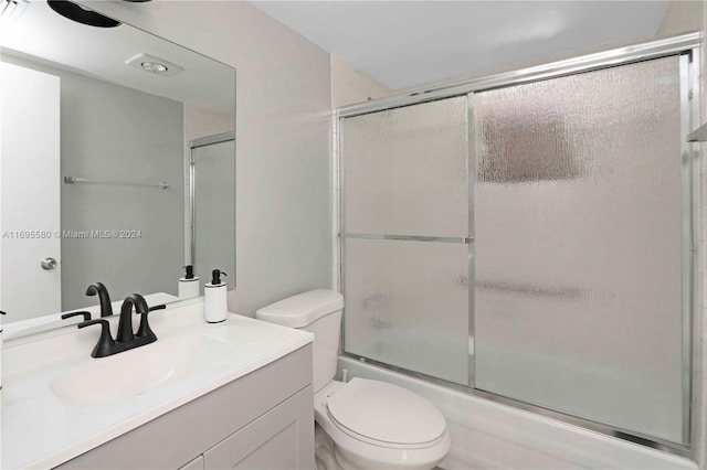 full bathroom featuring vanity, toilet, and shower / bath combination with glass door