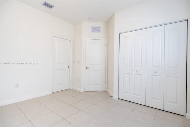 unfurnished bedroom featuring light tile patterned floors and a closet