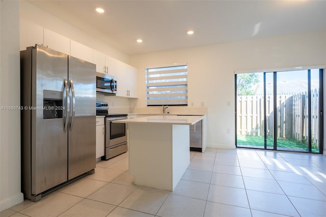 kitchen with light tile patterned flooring, white cabinetry, a kitchen island, and stainless steel appliances