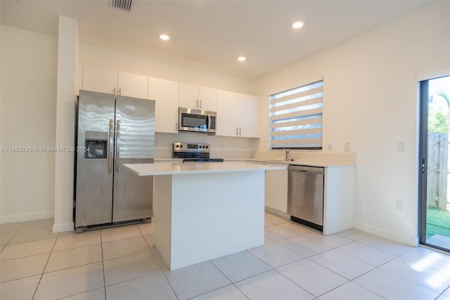 kitchen with white cabinetry, sink, stainless steel appliances, light tile patterned floors, and a kitchen island